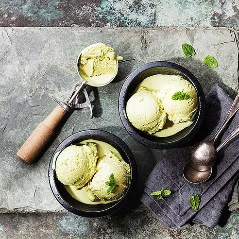 Eis Grüner Tee mit Minzblättern und Löffel für Eis auf Stein Schiefer Hintergrund