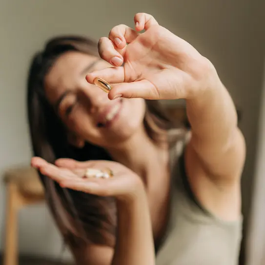 Lächelnde Frau mit Omega-3-Kapseln in der Hand