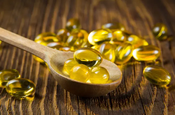 Omega-3 Kapseln auf Holzlöffel