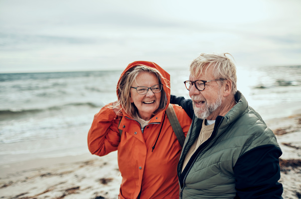 Älteres Ehepaar in Regenjacken am Strand